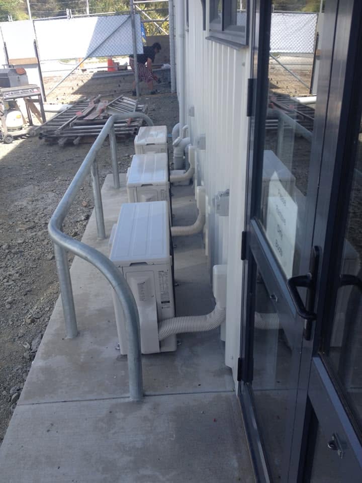 Outdoor units mounted along a walkway with a safety rail